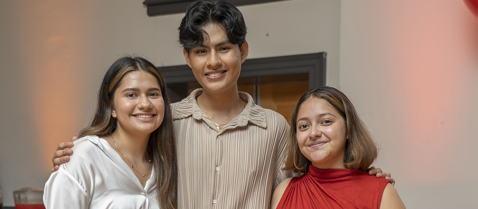 three students pose together with arms around each other