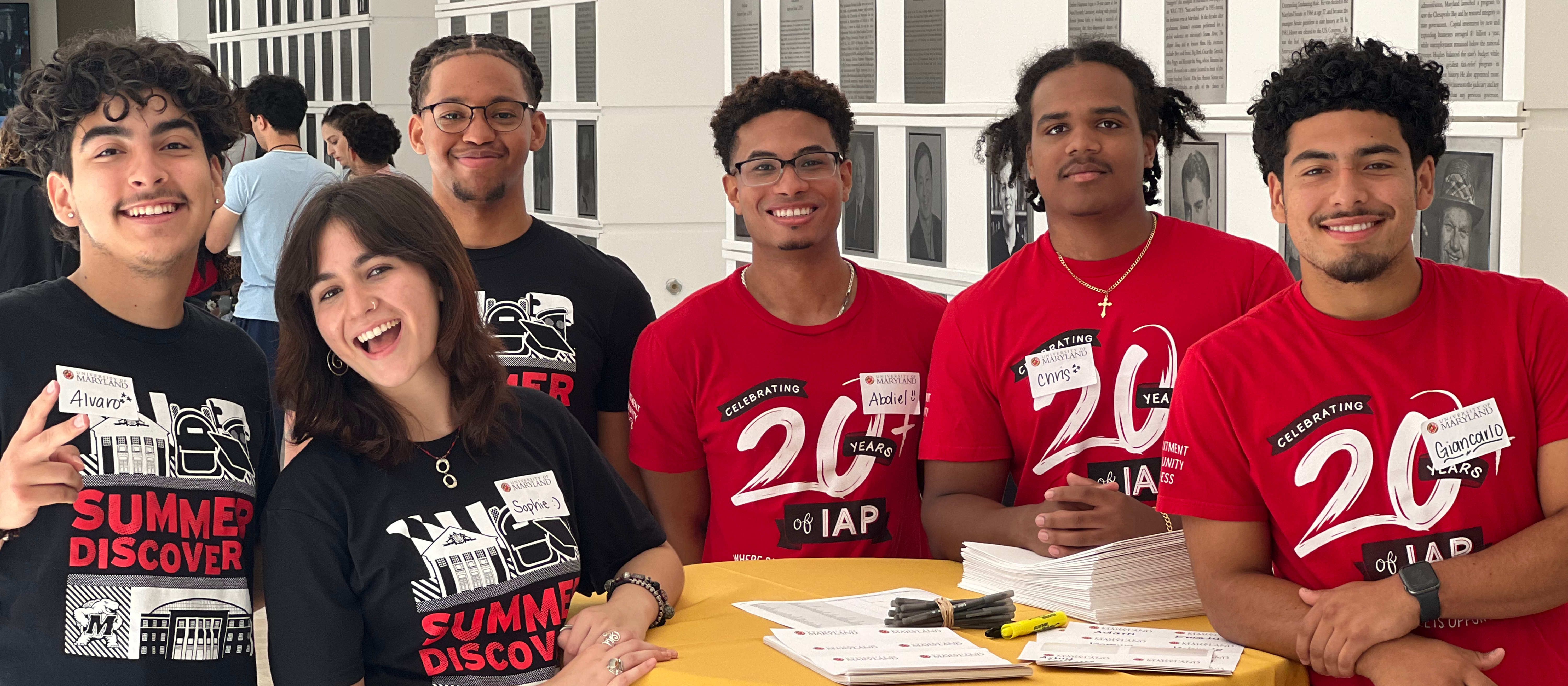 six students smiling, wearing branded t-shirts